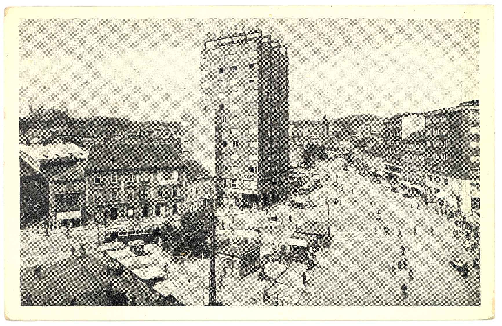 Historická fotografia dolnej časti dnešného Námestia SNP okolo roku 1936. V popredí sa nachádza Obchodný a obytný dom Manderla