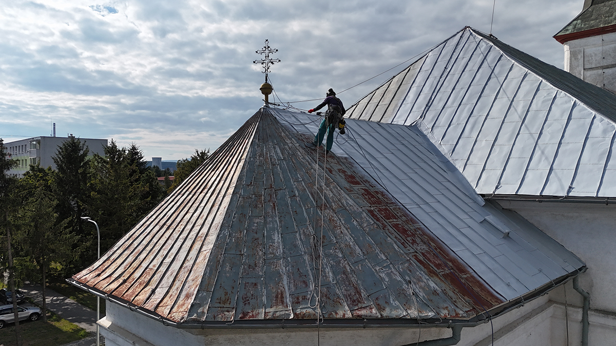 Výškový pracovník firmy MANKI pri renovácii poškodenej strechy kostola v Strážskom pomocou lezeckej techniky.