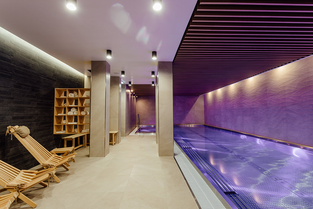 Wellness zóna v Boutique Hoteli Siglisberg: Luxusný interiér s moderným bazénom, tlmeným osvetlením a relaxačnými ležadlami, vytvorený pre maximálne pohodlie a oddych hostí.